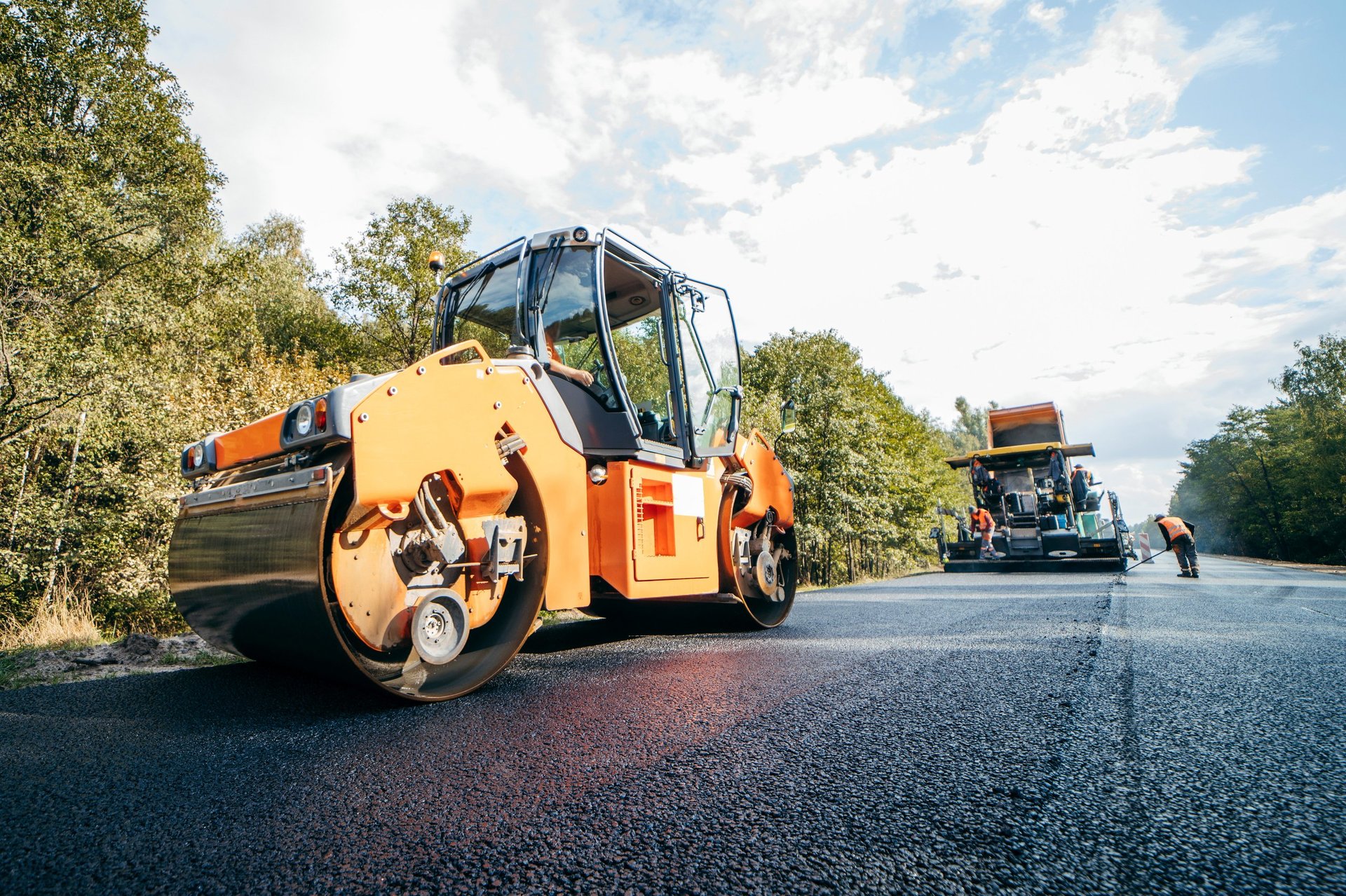 Vibratory asphalt rollers compacting new asphalt pavement on highway construction project