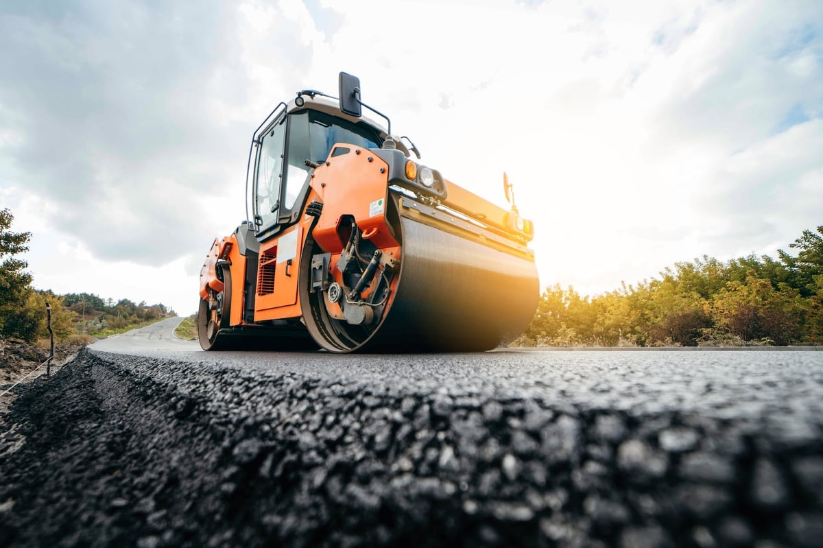 Highway construction with asphalt rollers compacting new pavement