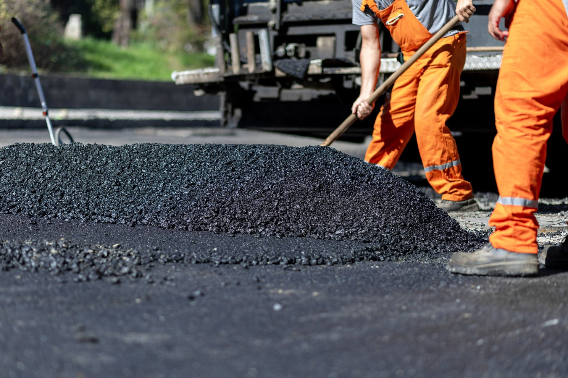 Construction workers spreading hot asphalt on road ensuring level finish for improved traffic flow