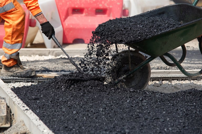 Construction workers spreading hot asphalt on road for infrastructure project