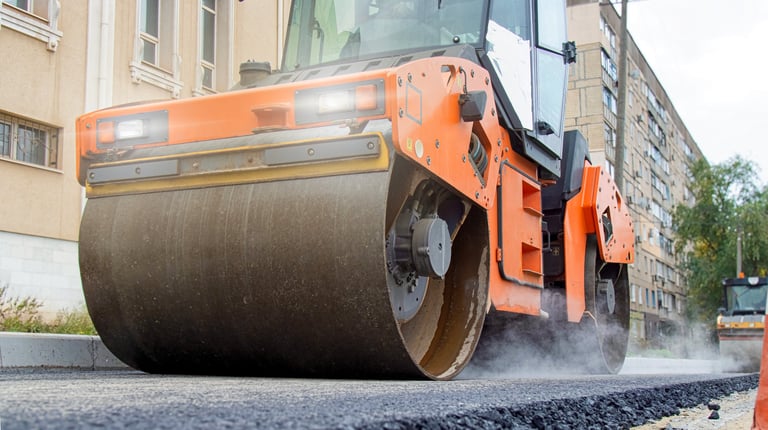Modern road roller compacting hot asphalt during urban street repair for infrastructure project